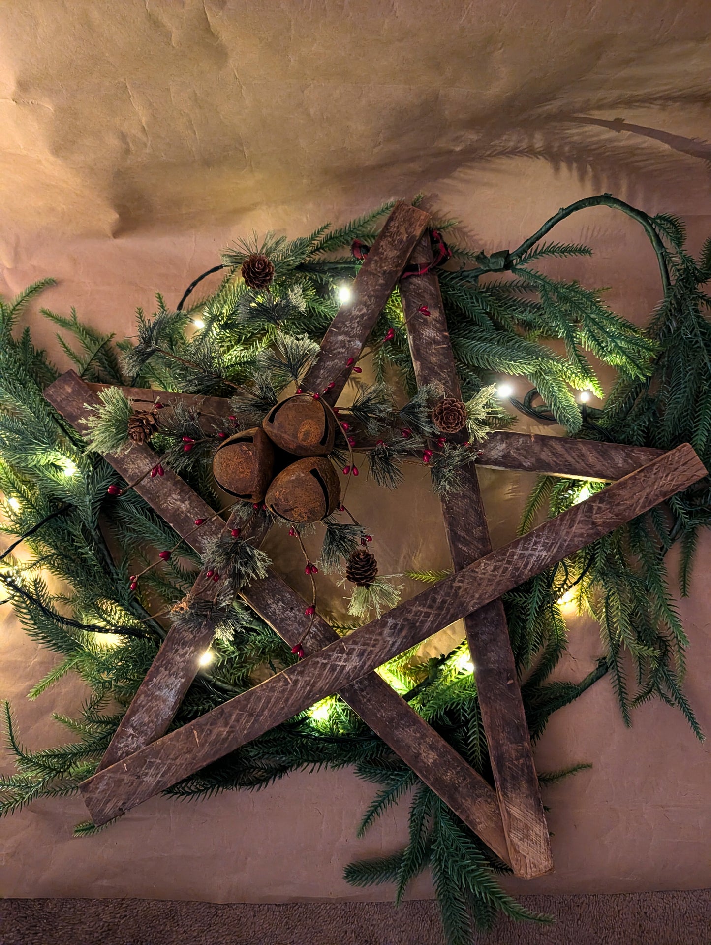 Decorative wreath with wooden cross and greenery on a neutral background