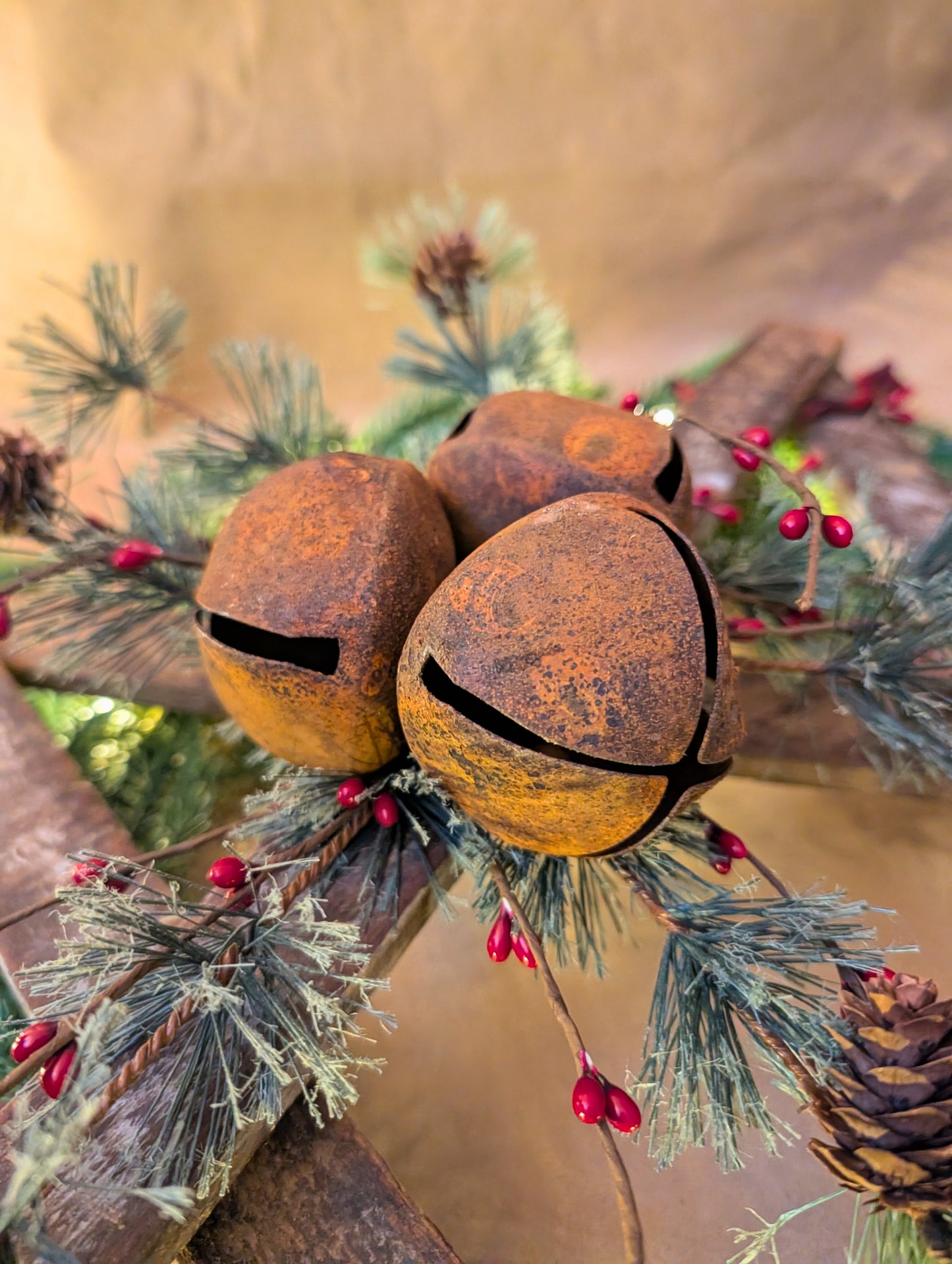 Rustic jingle bells on a branch with pine needles and berries against a blurred background