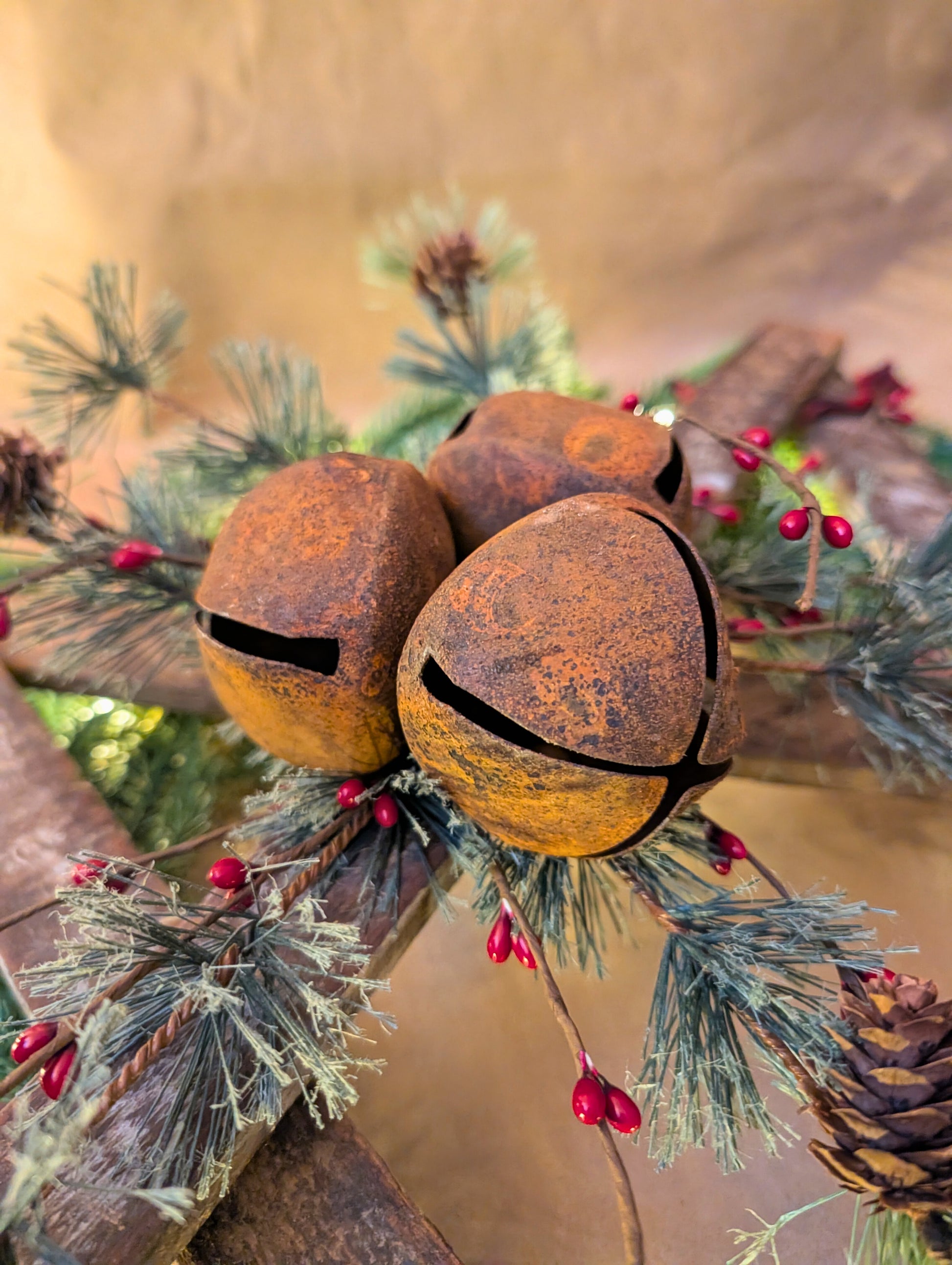 Rustic jingle bells on a branch with pine needles and berries against a blurred background