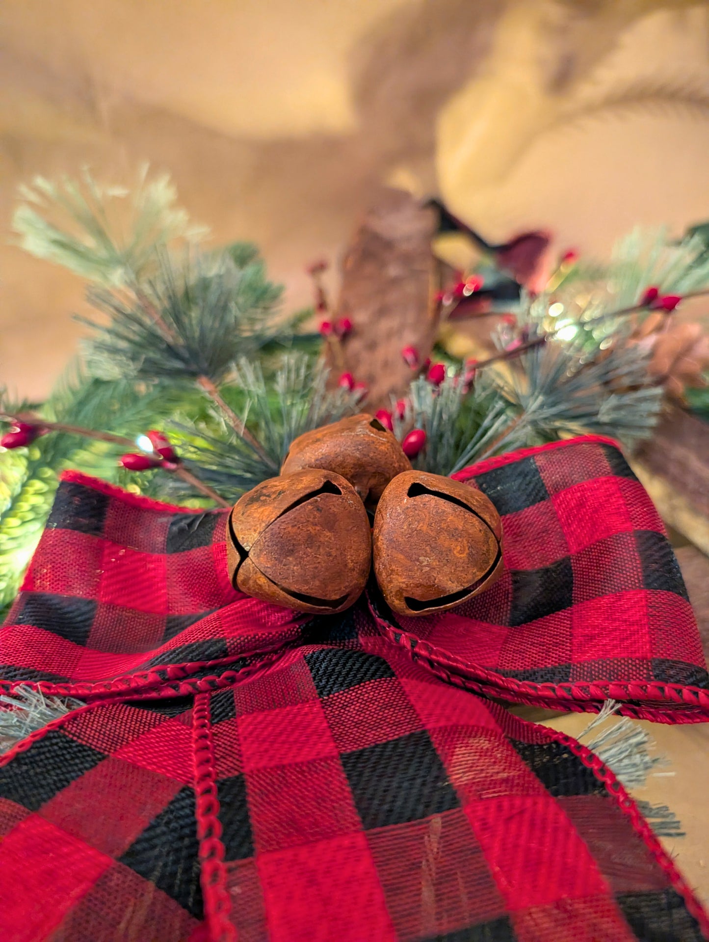 Decorative bow with red and black plaid ribbon and rusty bells on a blurred background