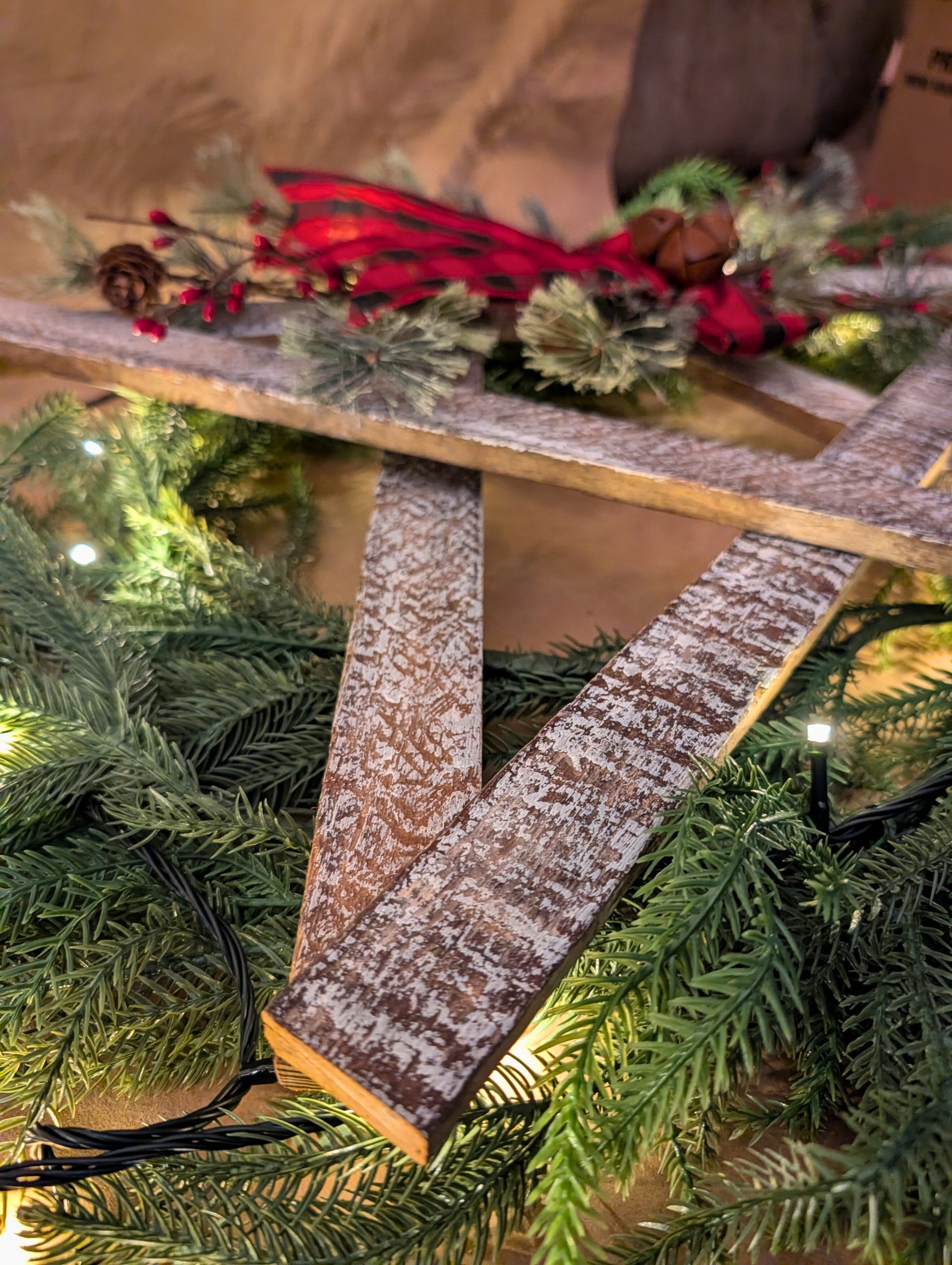 Decorative wooden ladder with greenery and red berries on a wooden surface.
