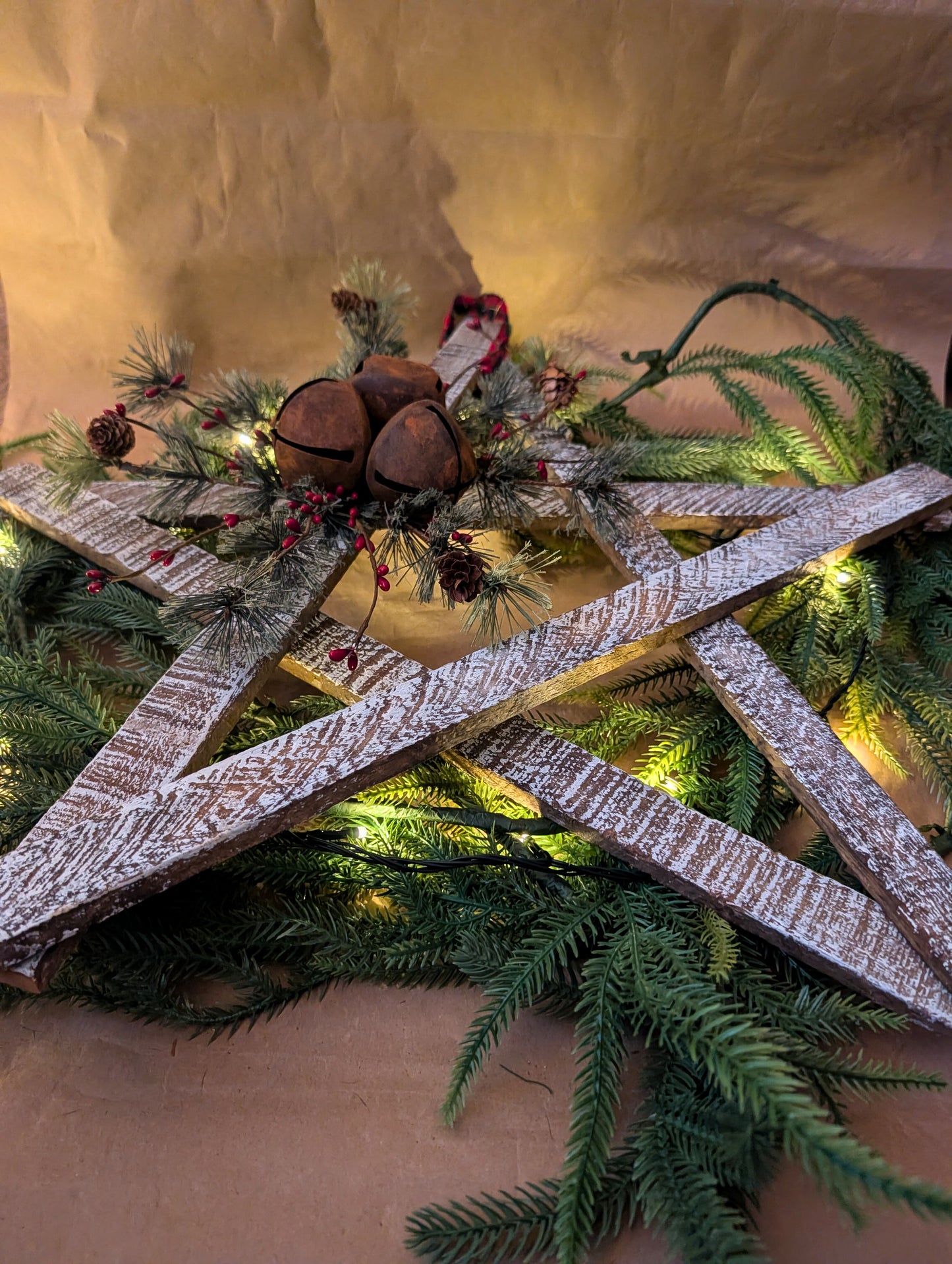 Decorative wreath with greenery, wooden elements, and pinecones on a neutral background