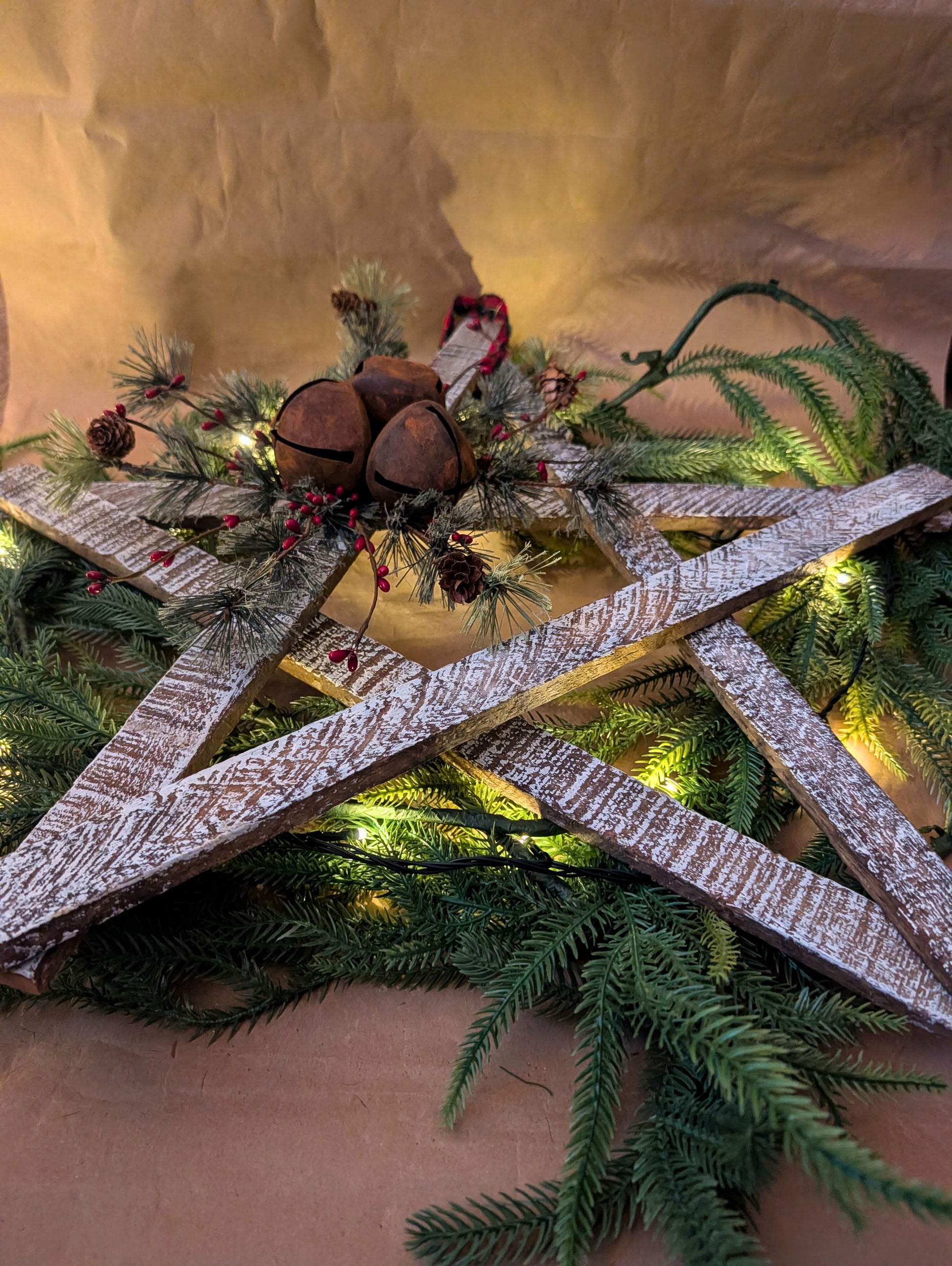 Decorative wreath with greenery, wooden elements, and pinecones on a neutral background