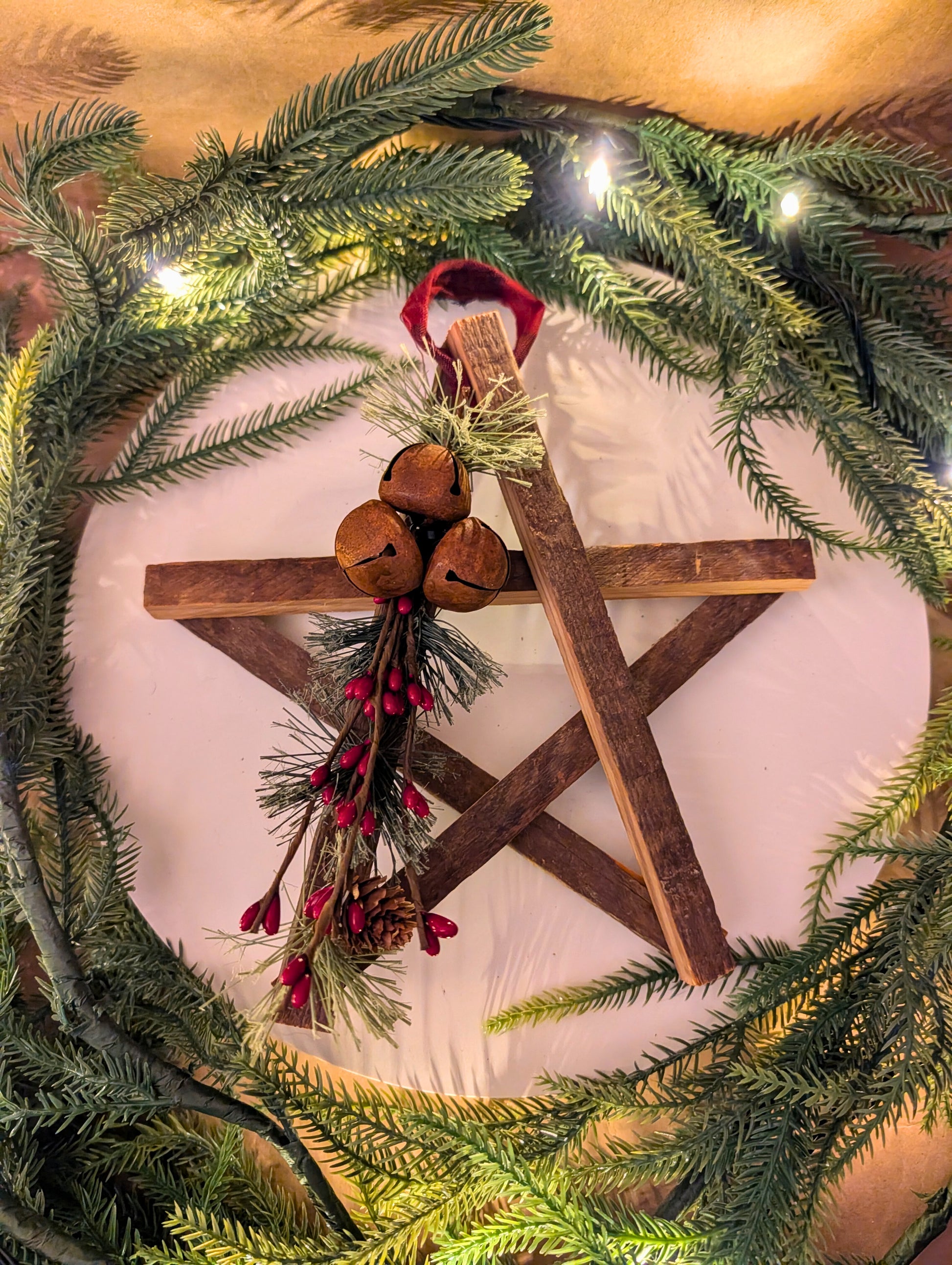 Decorative Christmas wreath with wooden star, pine cones, and lights.