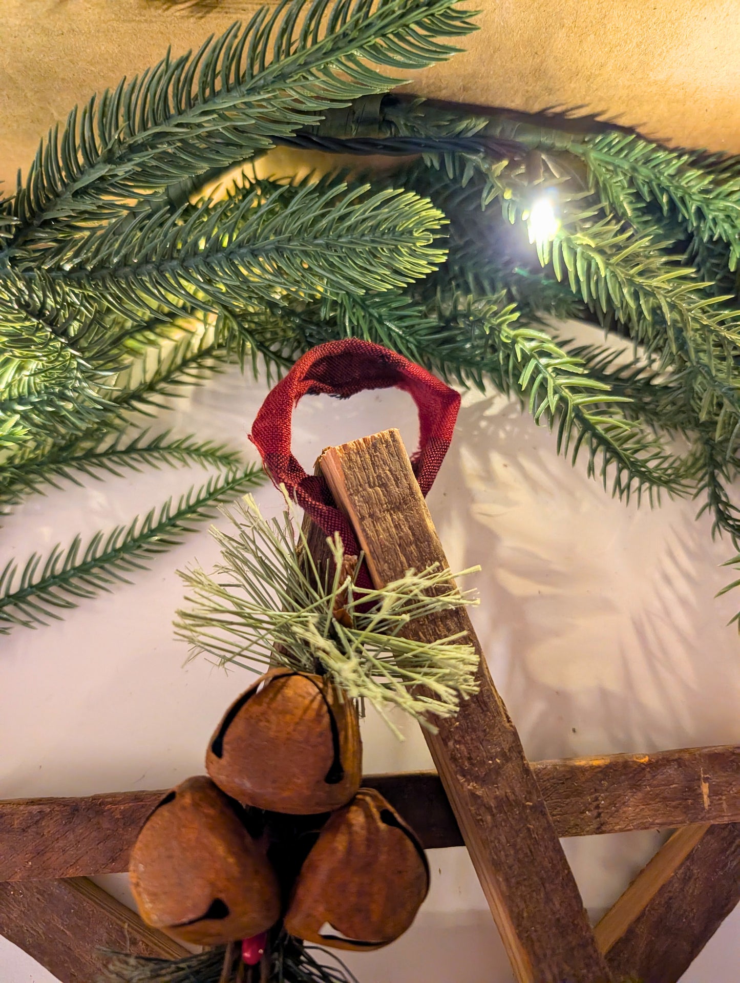 Decorative arrangement with greenery, wooden elements, and a red ribbon on a white background.