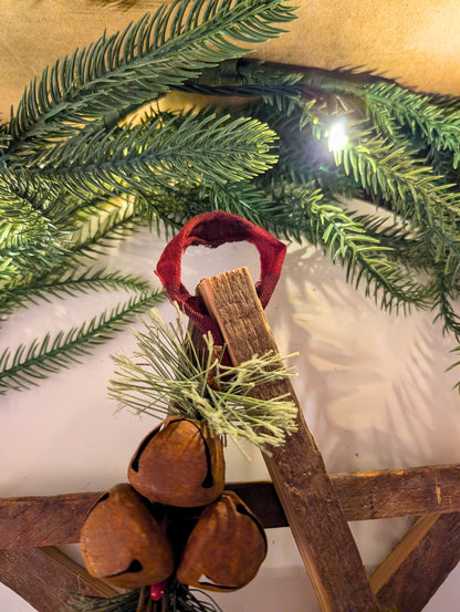 Decorative arrangement with greenery, wooden elements, and a red ribbon on a white background.