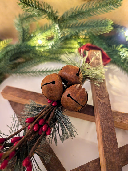 Decorative arrangement with brown bells, red berries, and greenery on a wooden surface.