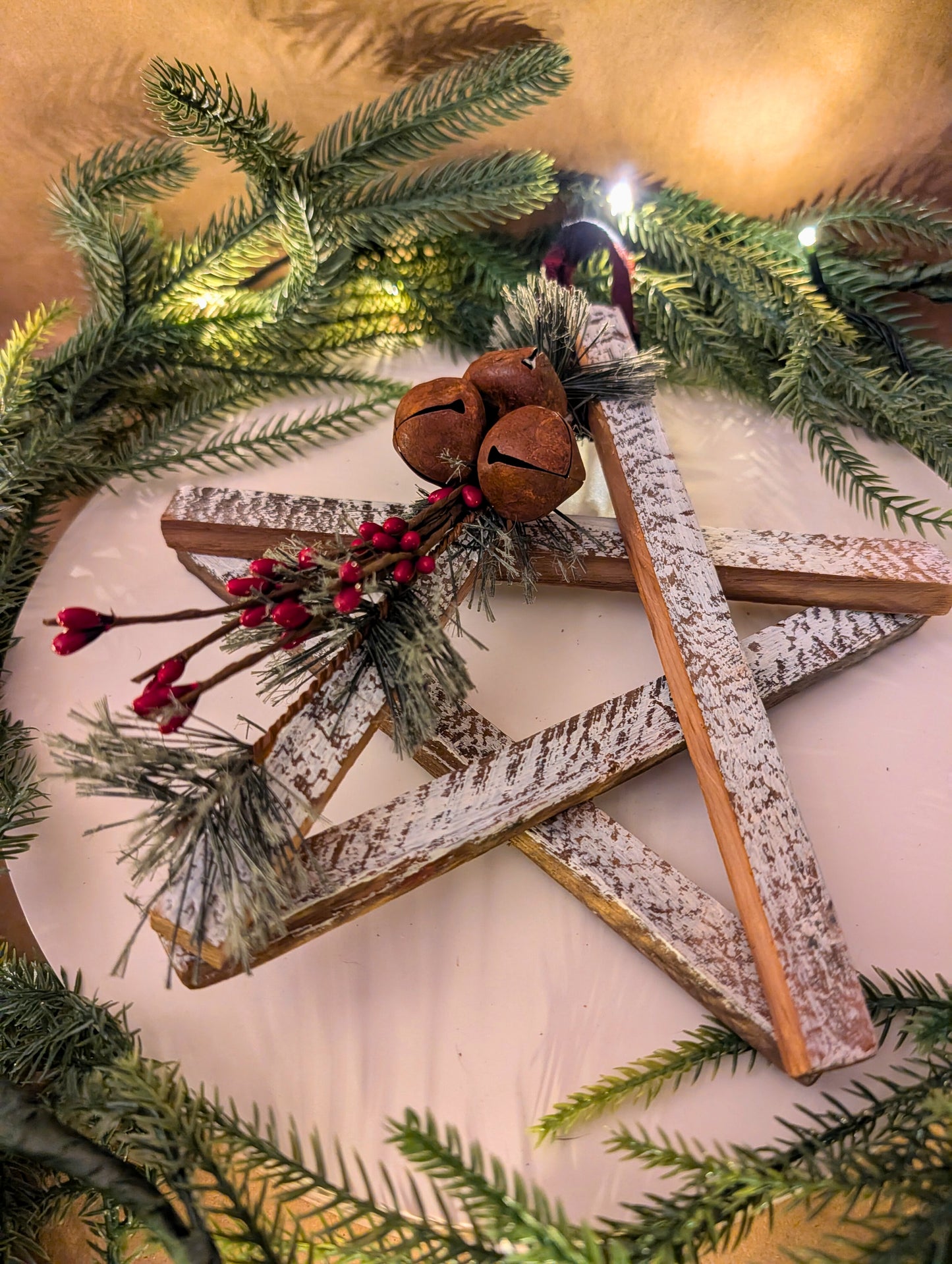 Decorative star with greenery, jingle bells, and red berries on a light background